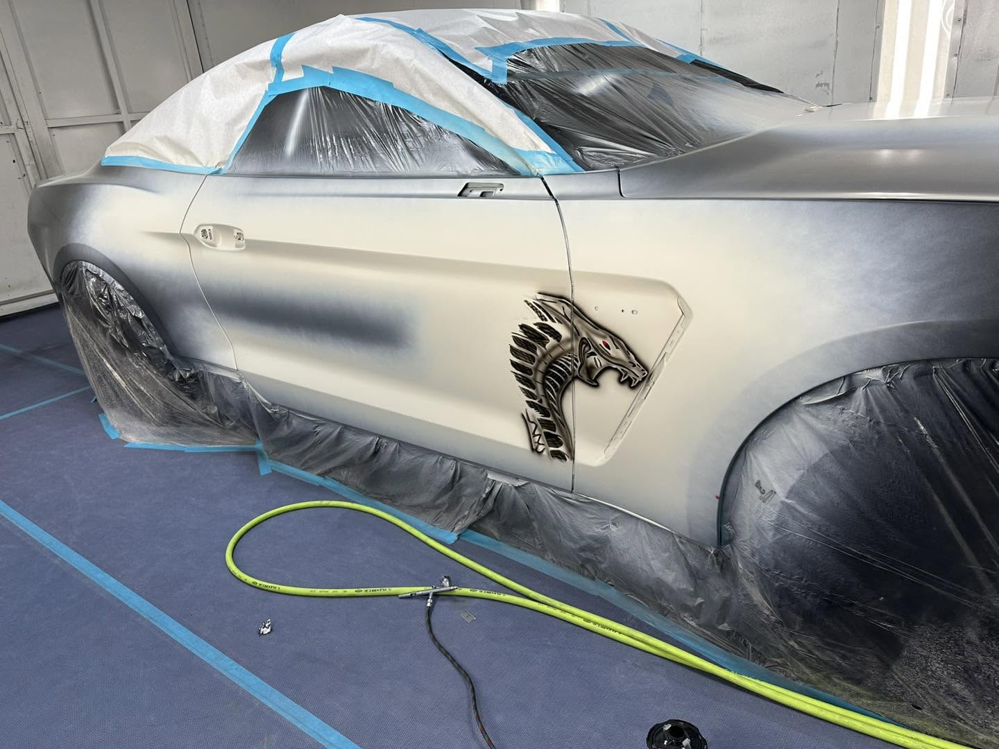 Phantom Blue Mustang passenger-side Cobra graphics in the Linear paint booth