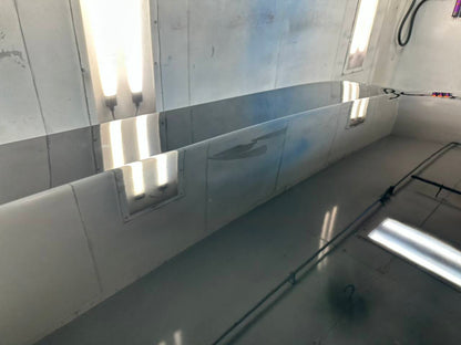 Glossy automotive panel reflecting paint booth lights