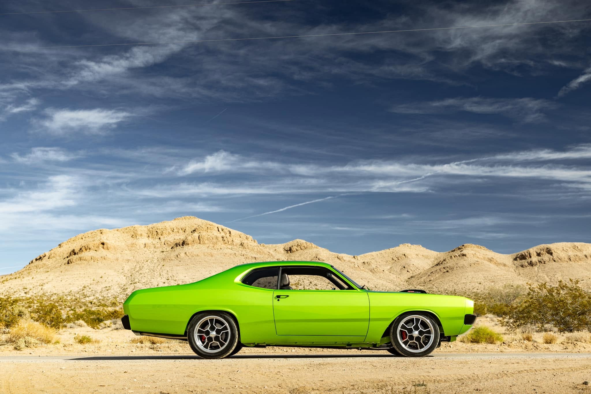 Side profile of the Green With Envy 1972 Dodge Demon on a desert road