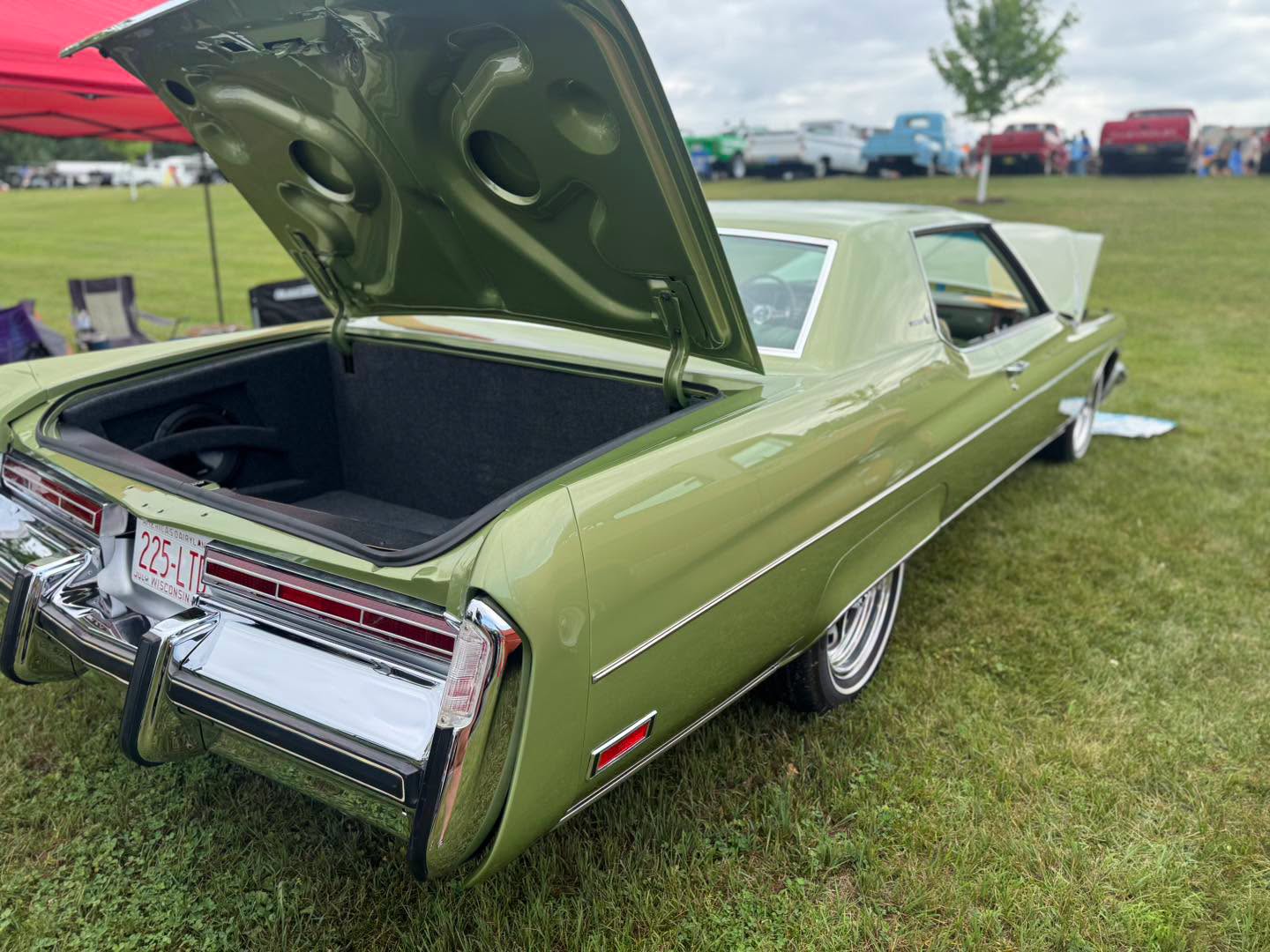 Rear three-quarter view of the Leaf Green Buick Electra with the trunk open at a car show