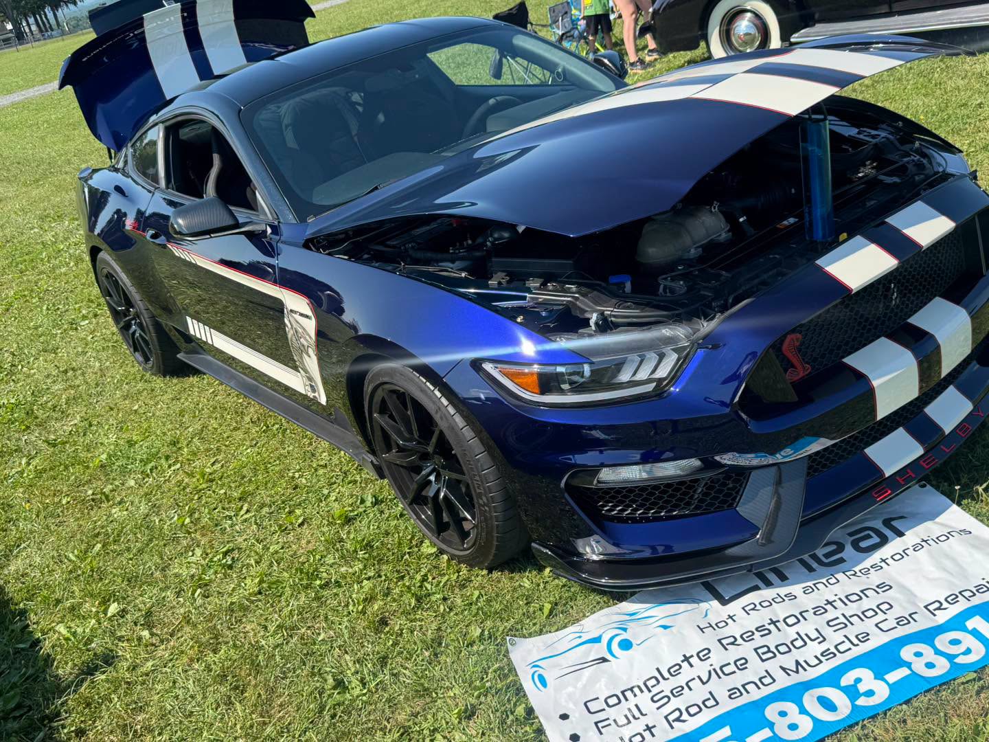 Front three-quarter view of the finished Phantom Blue GT350 with hood open at a car show