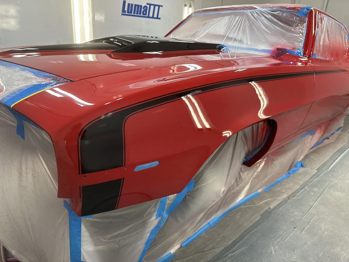 Solar Red Camaro body in the booth with the black hood and cowl graphics laid out